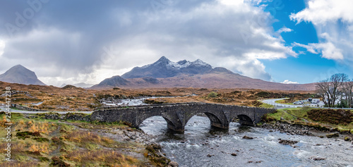 Old massive stone bridge crossing shallow river in Sligachan, Isle of Skye, Scotland