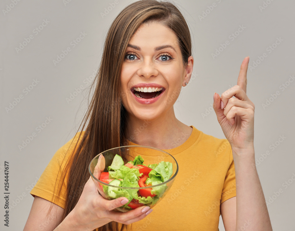 Smiling woman holding salad in glass bowl and pointing finger up. Smiling woman holding salad in glass bowl and pointing finger up.