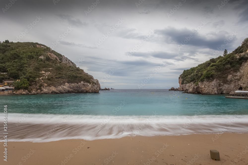 Paleokastritsa bay cliffs and beach with Kolyviri island background on a rainy day