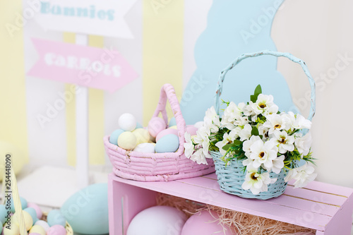 Happy easter! Large colorful baskets with Easter painted eggs and spring flowers. Easter bunny and big colorful eggs. Spring room decoration and easter decor. Spring home decor and spring flowers.