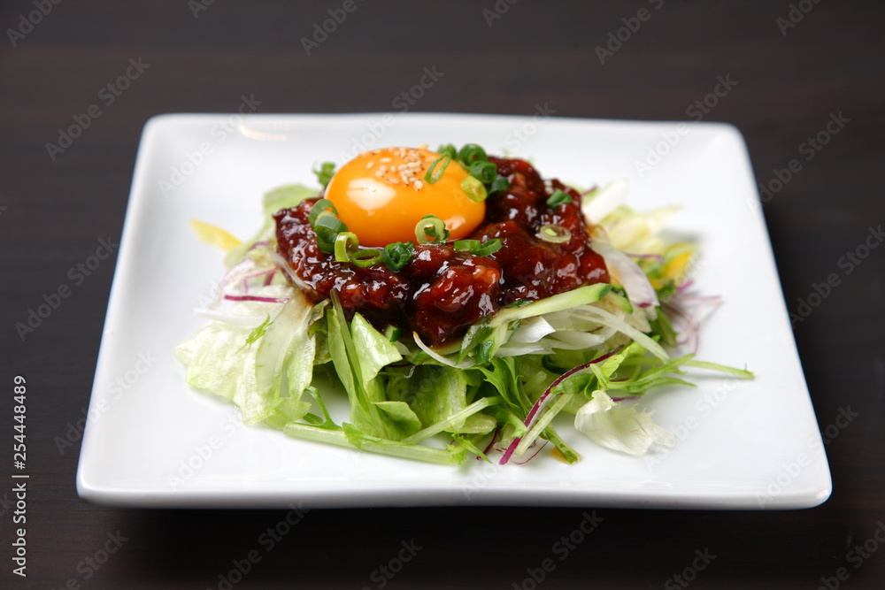 Korean dish of seasoned raw horse topped with an egg yolk