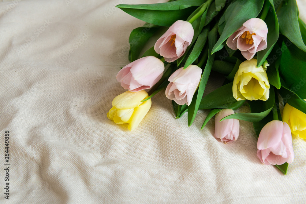 Spring flowers. Bouquet of pink yellow tulips on beige fabric background. Mother's Day, Valentines Day and Happy birthday background, copy space Spring flowers. Bouquet of pink yellow tulips on beige fabric background. Mother's Day, Valentines Day and Happy birthday background, copy space