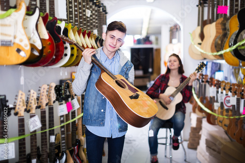 Teenagers examining guitars in shop