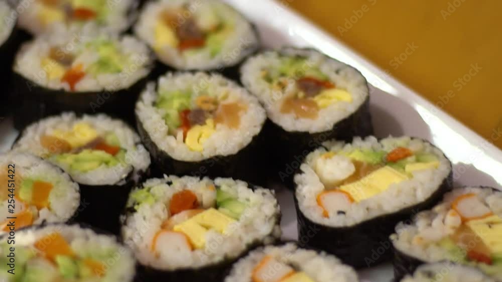 Slow Motion of delicious makizushi set with salmon served on white plate. Traditional rolled sushi Japanese food in restaurant. Nori roll with rice seeweed and fish in a gourmet menu.-Dan Slow Motion of delicious makizushi set with salmon served on white plate. Traditional rolled sushi Japanese food in restaurant. Nori roll with rice seeweed and fish in a gourmet menu.-Dan