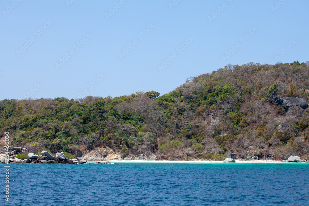 blue sea with white sand on the background of the jungle and rocks. Thailand Racha Island