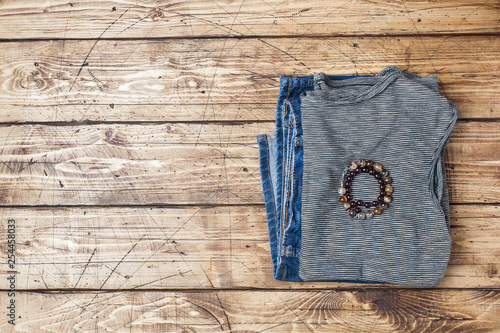Summer women's clothes. Flat lay fashion photo. Grey striped t-shirt and blue jeans on wooden background.