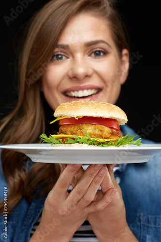 smiling woman holding burger on white plate