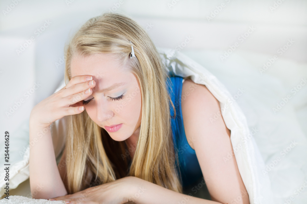Young Woman holding her head in pain or sadness, lying in bed Young Woman holding her head in pain or sadness, lying in bed