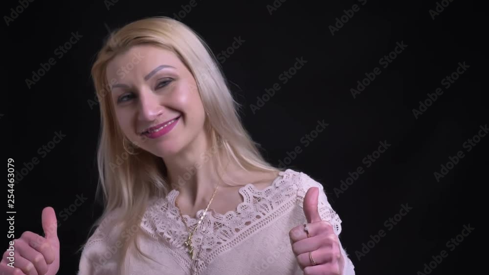 closeup shoot of middle aged caucasian female showing thumbs up and smiling while looking straight at camera closeup shoot of middle aged caucasian female showing thumbs up and smiling while looking straight at camera
