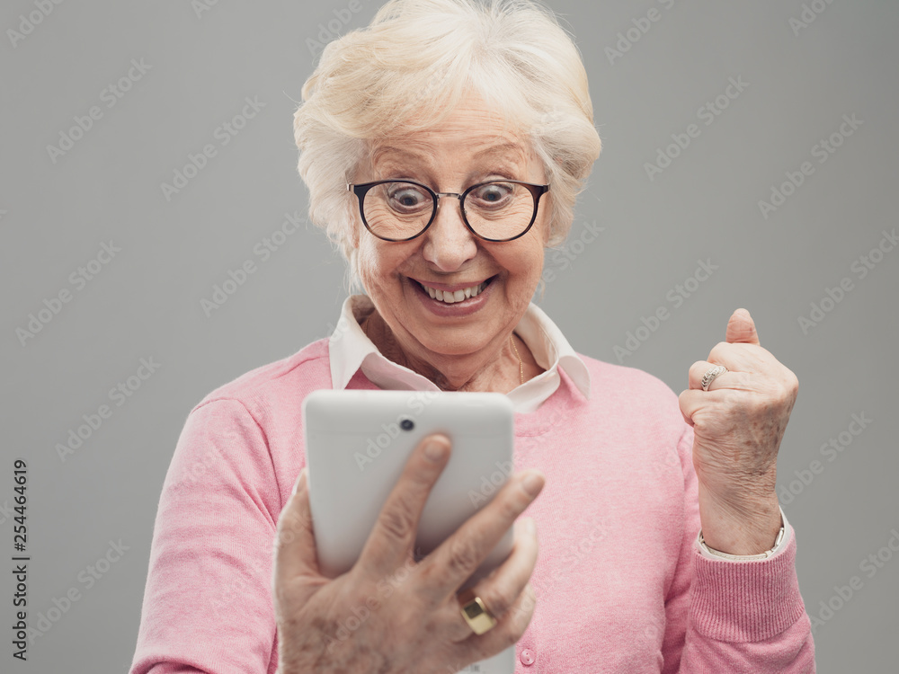 Happy surprised senior lady using a digital tablet Happy surprised senior lady using a digital tablet