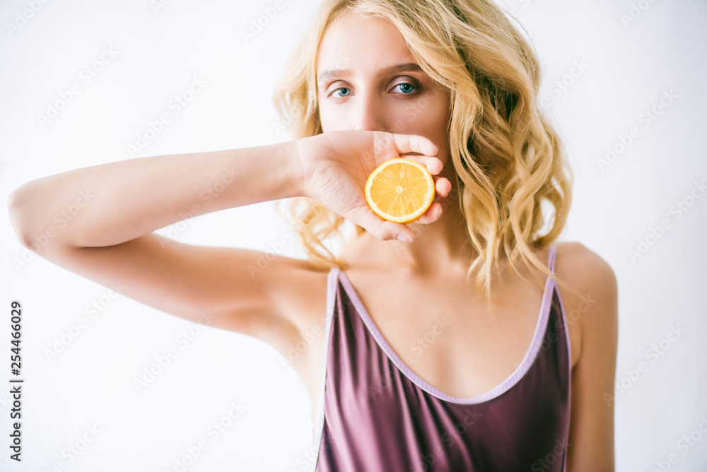Attractive young girl with blond hair in a bikini and lemon halves in her hands Attractive young girl with blond hair in a bikini and lemon halves in her hands