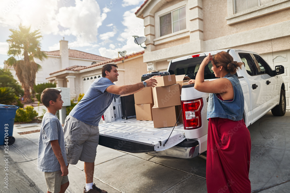 hispanic family unloading pickup truck and moving into new house in las vegas - obrazy, fototapety, plakaty 