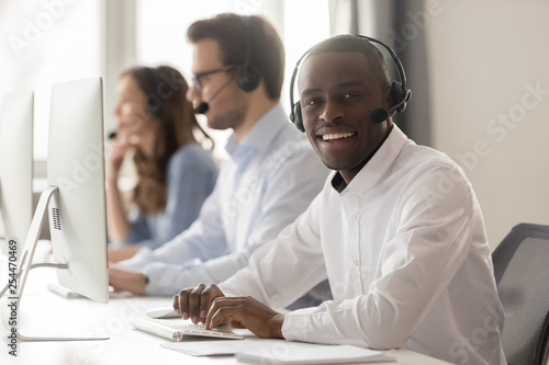 Happy african call center agent in headset posing at workplace