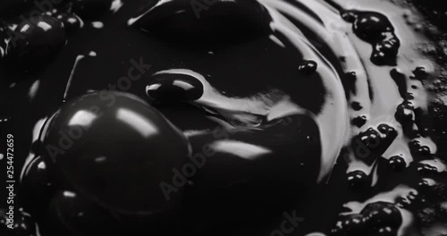 Dark oil dropping into a seething pond of black liquid