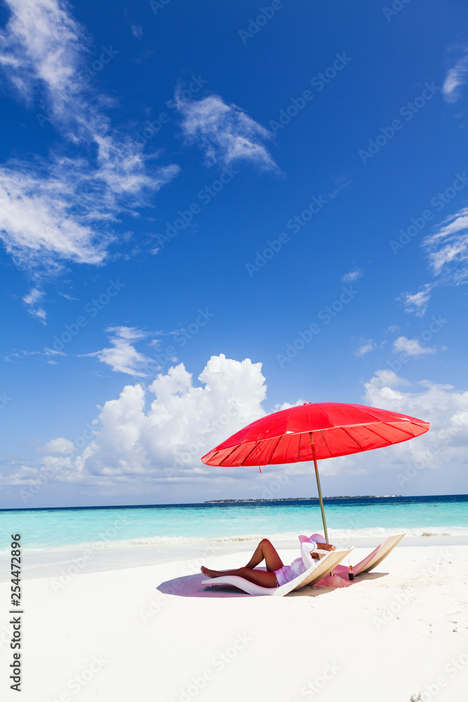 Woman enjoying on the tropical beach under red umbrella
