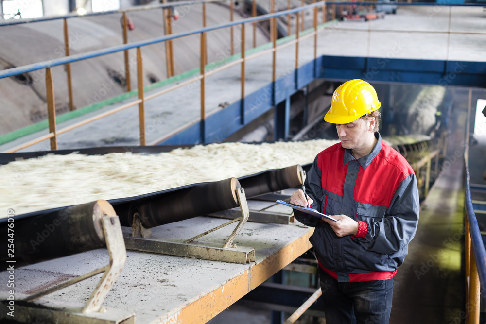 Transport of sugar on the production line, worker writes the quality information Transport of sugar on the production line, worker writes the quality information