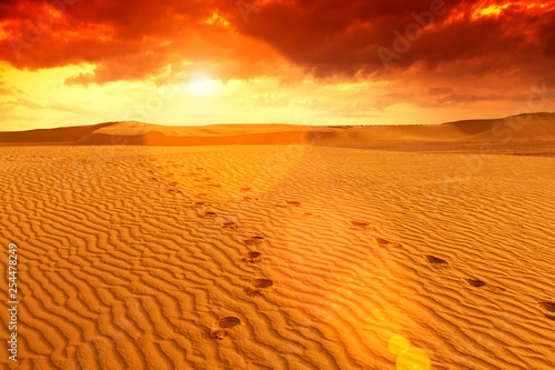 sunset in desert, feet print in sand