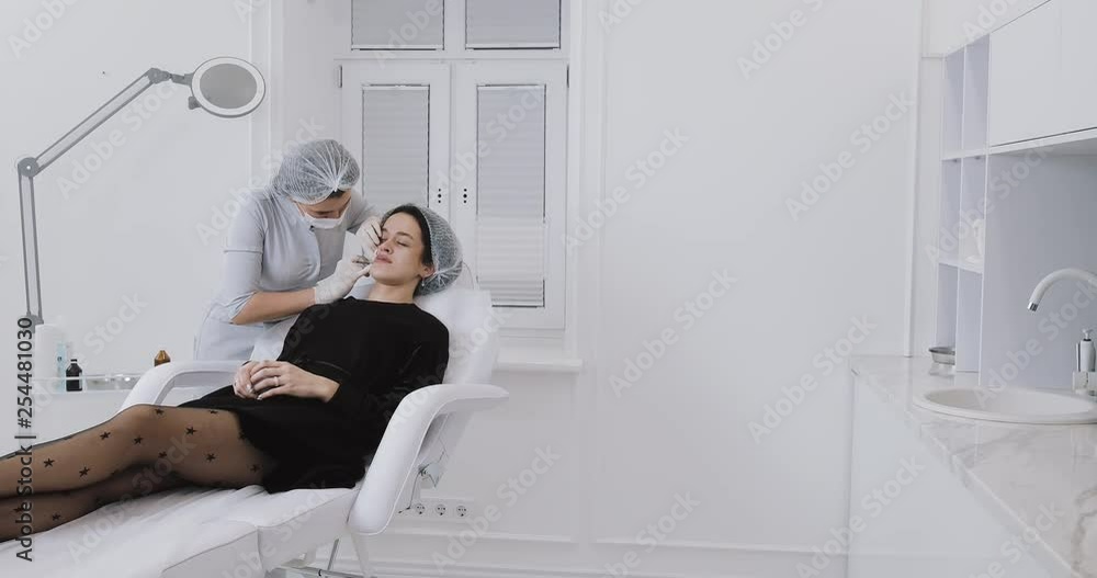 Lip Augmentation. The doctor cosmetologist makes lip augmentation procedure of a beautiful woman in a beauty salon. Cosmetic beauty injection concept Lip Augmentation. The doctor cosmetologist makes lip augmentation procedure of a beautiful woman in a beauty salon. Cosmetic beauty injection concept