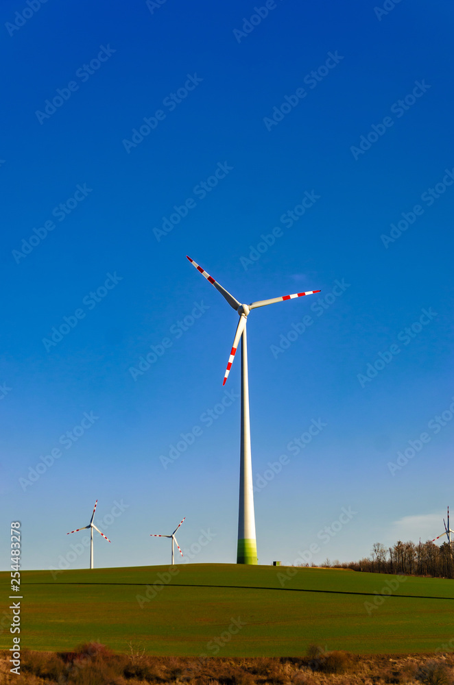 Windmill in a green field against a blue sky. Naturally friendly resource extraction systems. Windmill in a green field against a blue sky. Naturally friendly resource extraction systems.