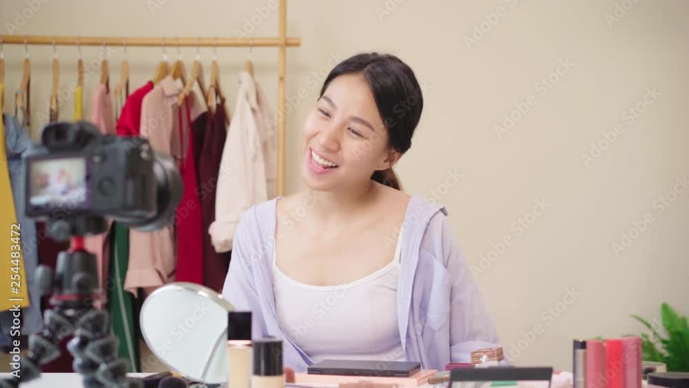Beauty blogger present beauty cosmetics sitting in front camera for recording video. Happy beautiful young Asian woman use cosmetics review make up tutorial broadcast live video to social network. Beauty blogger present beauty cosmetics sitting in front camera for recording video. Happy beautiful young Asian woman use cosmetics review make up tutorial broadcast live video to social network.