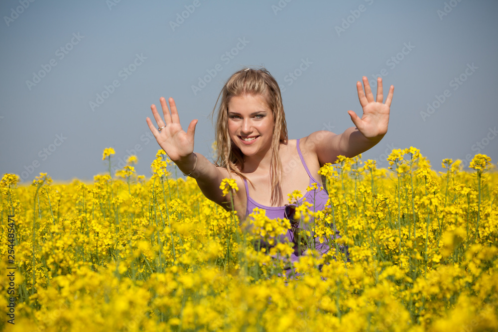 Naklejka premium Portrait of young, smiling woman in the Canola oil seed rape field