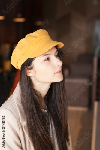 A young beautiful woman came to the cozy cafe in the morning to eat breakfast with a delicious granola sitting at a table near a large bright window