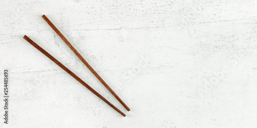 Wallpaper Mural Flat lay photo - pair of dark wood chopsticks on white board. Wide banner for asian / chinese food, space for text on right. Torontodigital.ca