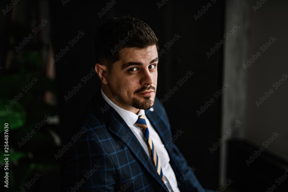 A handsome man in a blue suit in a cage posing in the Studio. Business portrait. A handsome man in a blue suit in a cage posing in the Studio. Business portrait.