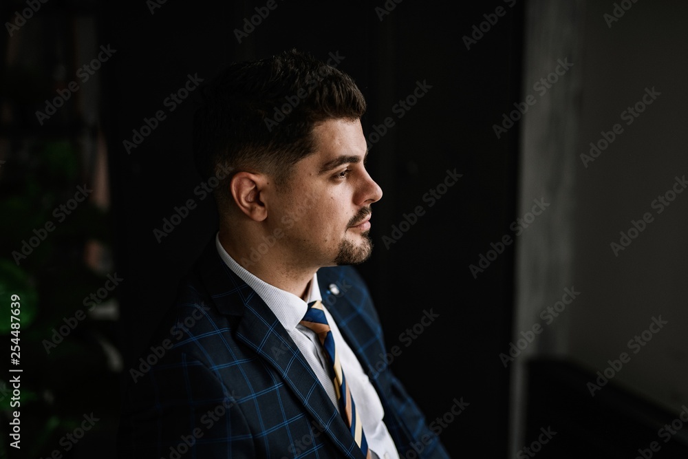 A handsome man in a blue suit in a cage posing in the Studio. Business portrait. A handsome man in a blue suit in a cage posing in the Studio. Business portrait.