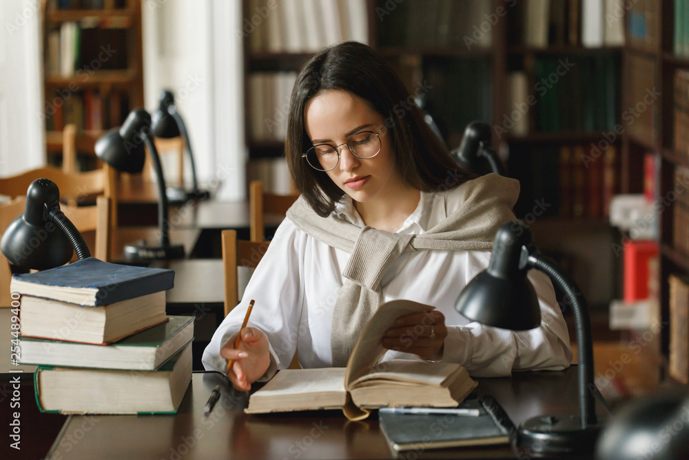 Pretty female student with books working in a high school library Pretty female student with books working in a high school library