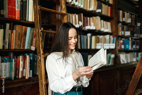 Brunette young woman looking for information in books at the library