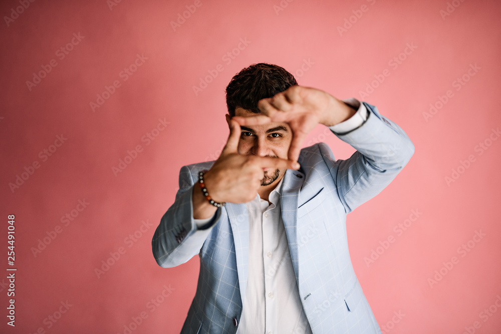 A handsome man in light jeans and a blue jacket posing on a pink background. Men's business photo shoot in the Studio. A handsome man in light jeans and a blue jacket posing on a pink background. Men's business photo shoot in the Studio.