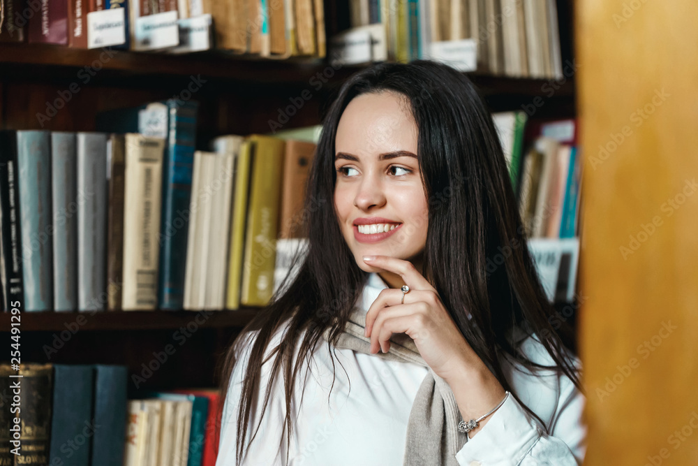 Thoughtful girl chooses books for the exam Thoughtful girl chooses books for the exam