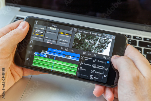 Black smartphone in hand. On-screen video editing program photo