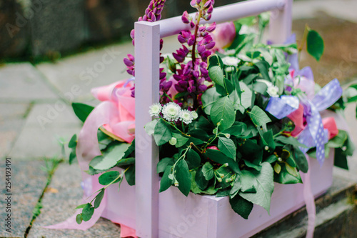Beautiful flowers in a purple wooden basket outdoors.