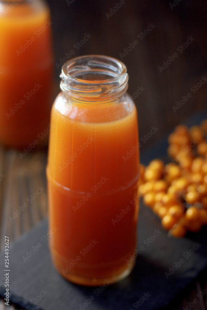 Sea buckthorn juice in a jar on a dark wooden background. Sea buckthorn juice in a jar on a dark wooden background.