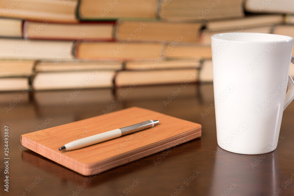 Old books on wooden table with tea and open notebook