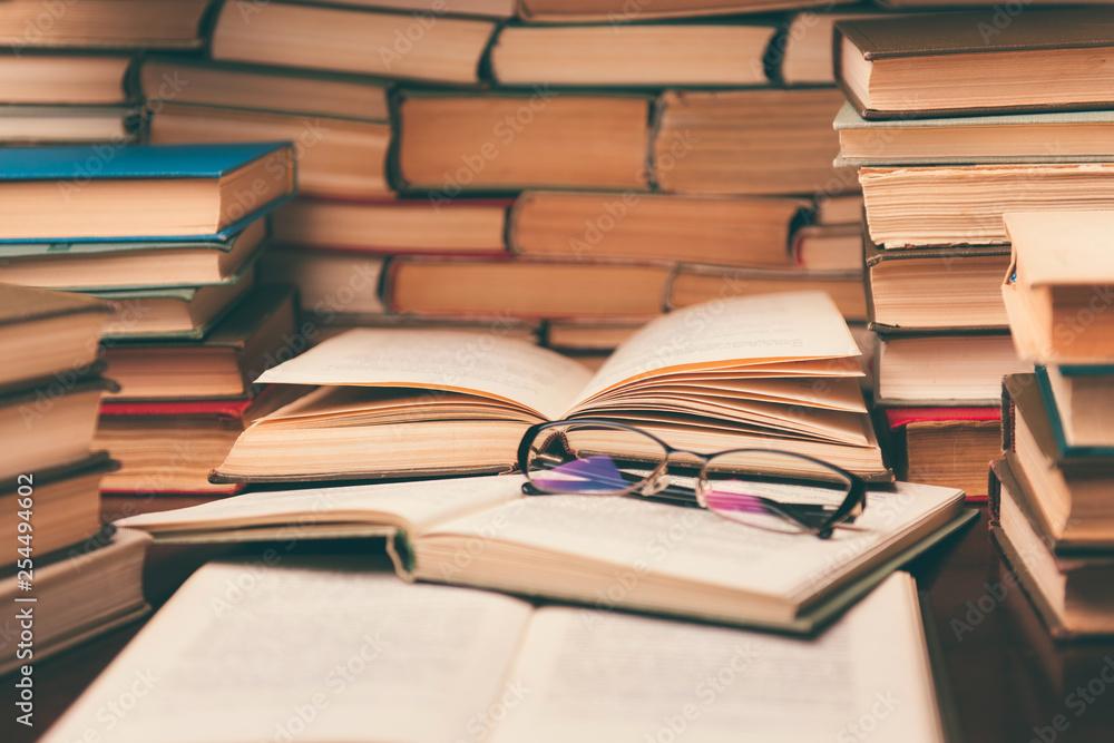 Open book and glasses on wood desk in the library room with blurred focus for education background and back to school concept Open book and glasses on wood desk in the library room with blurred focus for education background and back to school concept