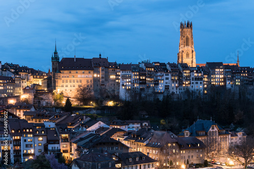 Twilight over the Fribourg old town and the illuminated Cathedral Saint Nicolas in Switzerland. Fribourg is one of the best preserved medieval old town in the country.