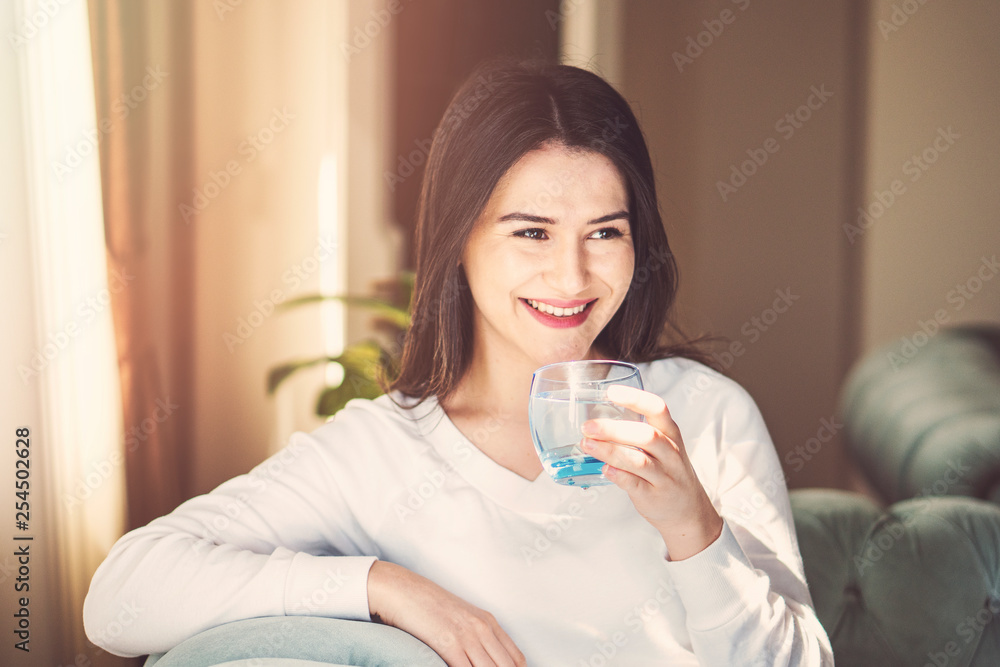 Girl drinking water sitting on a couch at home