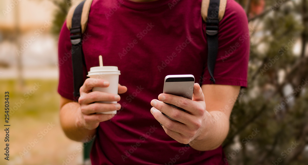 Man is using his mobile phone while holding a cup of coffee Man is using his mobile phone while holding a cup of coffee