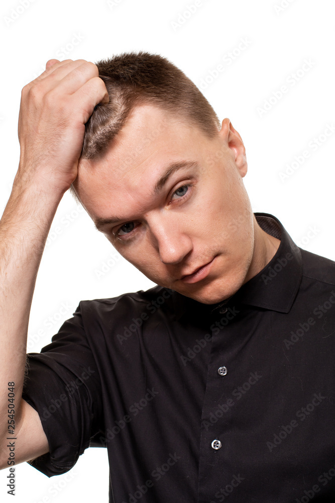 Handsome young man in a black shirt is making faces, while standing isolated on a white background Handsome young man in a black shirt is making faces, while standing isolated on a white background