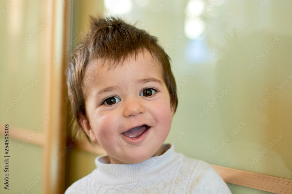 Closeup indoor portrait of a baby boy with naughty hair. The various emotions of a child are laughter, joy, delight, suspicion, disappointment, enthusiasm, chagrin, seriousness. Infant.