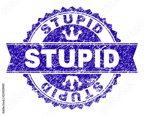 STUPID rosette stamp watermark with grunge texture. Designed with round rosette, ribbon and small crowns. Blue vector rubber watermark of STUPID tag with dust texture.