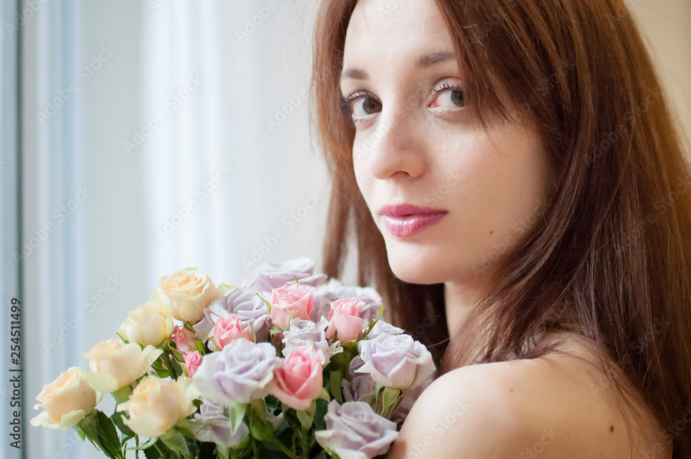 Attractive young brunette woman looking at the camera holding a bouquet of the flowers Attractive young brunette woman looking at the camera holding a bouquet of the flowers