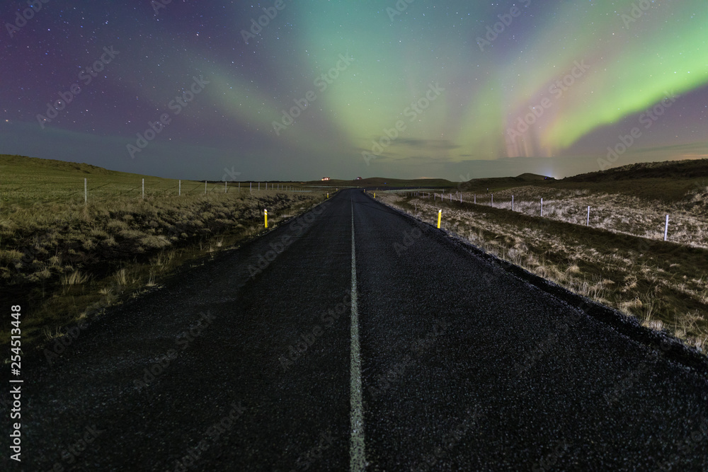 Northern light above the road in Norway A quiet road in Scandinavia with a spectacular Northern Light Aurora display lighting up the night sky. A popular destination within the arctic circle for hunt