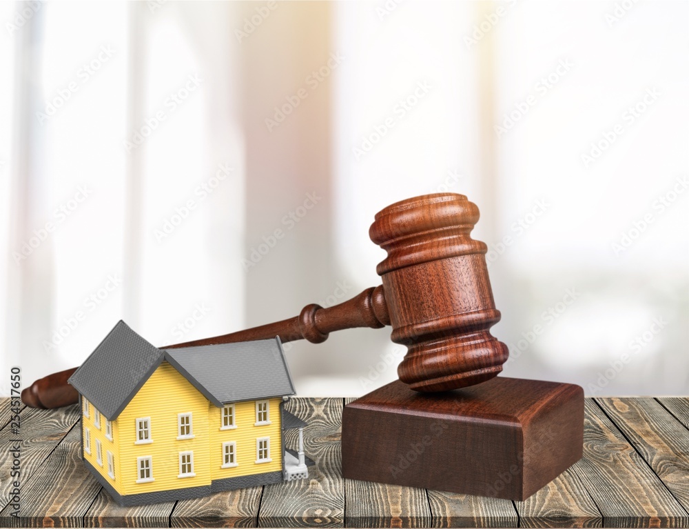 Wooden judge gavel and toy house on background Wooden judge gavel and toy house on background