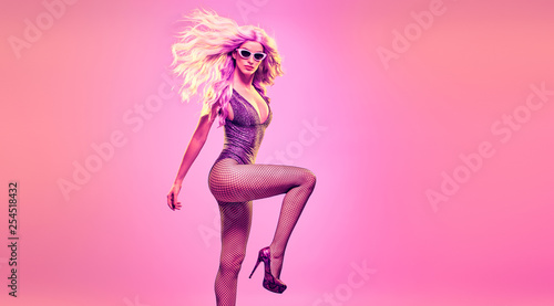 Fashion. Excited Woman in colorful neon pink purple light dance. Beautiful model with party makeup. Disco girl in stylish bodysuit enjoy music, nightlife. Creative fashionable concept, uv neon