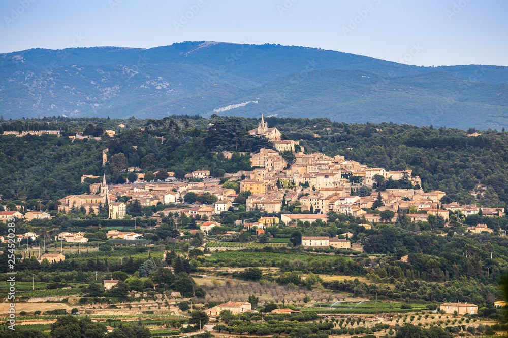 Panoramic view of medieval village Bonnieux in department Vaucluse, fields in the foreground, mountains in the background. Provence, France. Travel France.