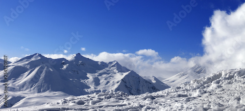 Panoramic view on snowy mountains and blue sky with sunlit clouds © BSANI